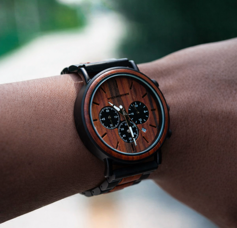 Wooden watch with black strap on wrist against a blurred natural background