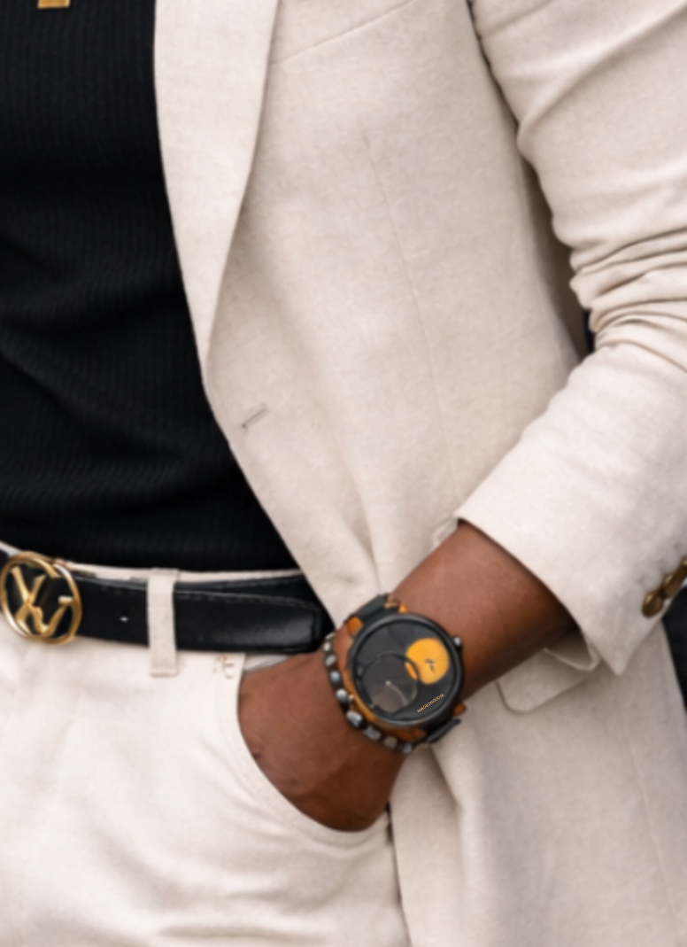 Man wearing a light-colored suit with sunglasses and gold jewelry in an urban setting