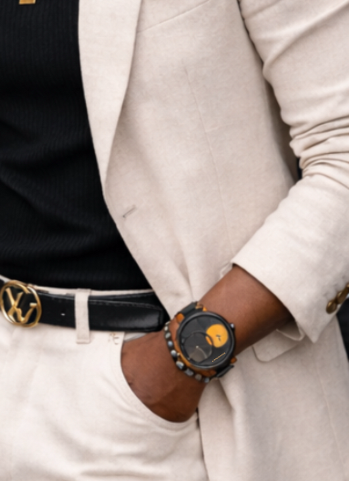 Man wearing a light-colored suit with sunglasses and gold jewelry in an urban setting